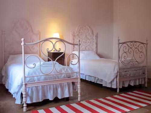 two white beds in a bedroom with a lamp at Castello Sonnino in Montespertoli