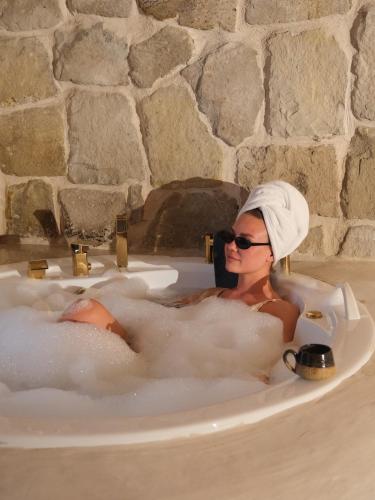 Eine Frau sitzt in einer Badewanne in der Unterkunft Doda Artisanal Cave Hotel 14 Plus in Ortahisar