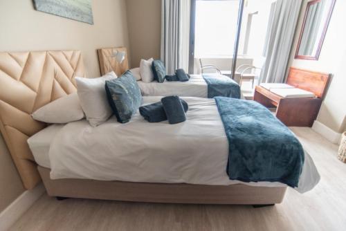 a bedroom with two beds with blue pillows at Beach View Apartment 205 in Swakopmund