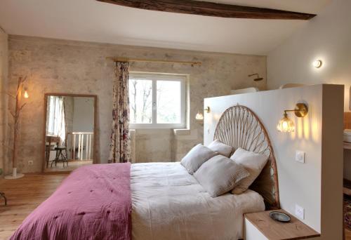 a bedroom with a large bed with a pink blanket at Small country house with authentic charm in Baurech