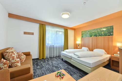 a hotel room with two beds and a couch at Hotel Ludwigshof & Luvina in Trodena
