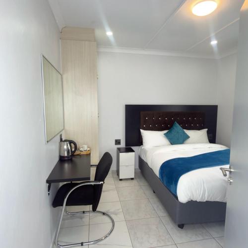 a bedroom with a bed and a desk and a chair at Cozy Villa Lodge in Edenvale