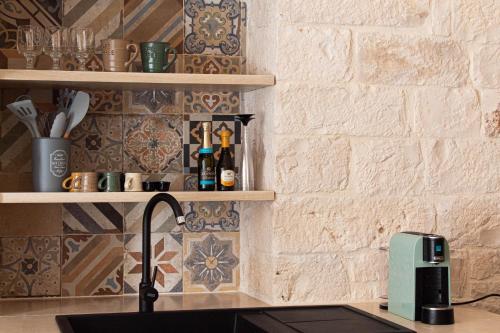 a kitchen counter with a sink and a wall with tiles at Aqua Suite - Stone Spa - A Few Minutes from Polignano, Monopoli & Alberobello in Castellana Grotte