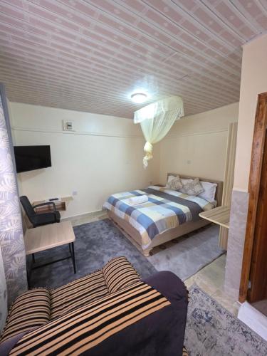 a room with two beds and a couch and a tv at Rosemond cottages eldoret in Eldoret