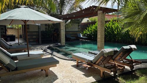 a pool with two lounge chairs and an umbrella at ABG Villas - Agrowisata Amed in Amed