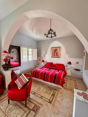a bedroom with a red bed and an arched ceiling at Chambre d'hôtes, Dar l'air du temps in Aghīr