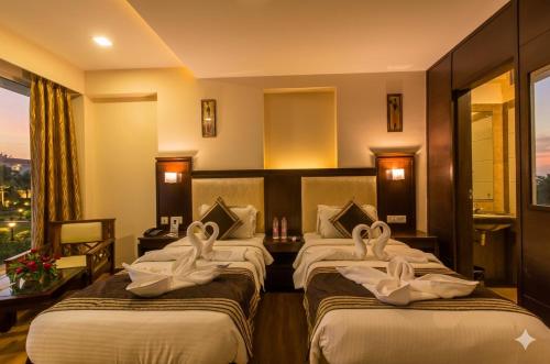 a hotel room with three beds with swans on them at Hotel Golden Manor-City Center Bani Park in Jaipur