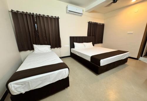 two beds in a hotel room withskirts at Nandha Grande Elite in Udumalaippettai