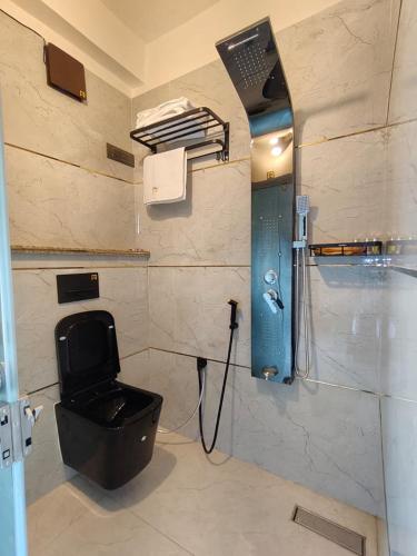 a bathroom with a black toilet and a shower at Hotel Joy Guru Inn in Durgāpur