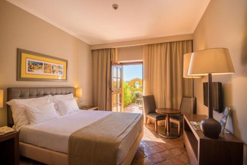 a hotel room with a bed and a sliding glass door at Vila Gale Albacora in Tavira