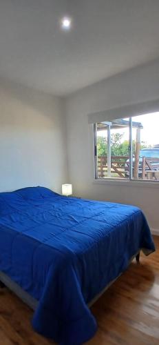 a blue bed in a bedroom with a large window at Piedra de Luna o Sur in Villa Serrana