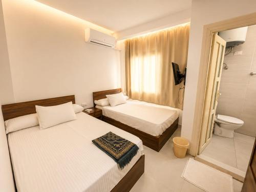 a hotel room with two beds and a toilet at vila hotel city in Cairo