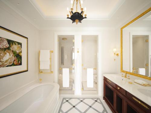 a bathroom with a tub and a sink and a chandelier at The Ritz London in London