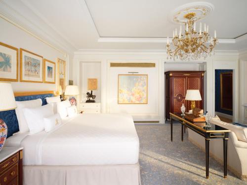 a bedroom with a bed and a desk and a chandelier at The Ritz London in London