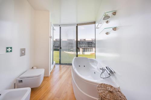 a white bathroom with a tub and a toilet at Pedrinhas Village by Geyra in Esposende