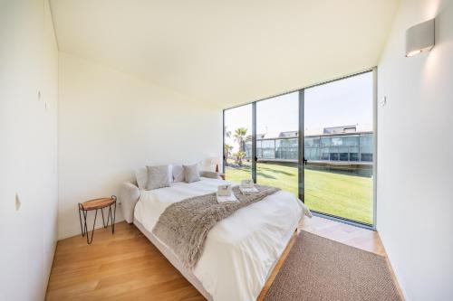 a bedroom with a bed and a large window at Pedrinhas Village by Geyra in Esposende
