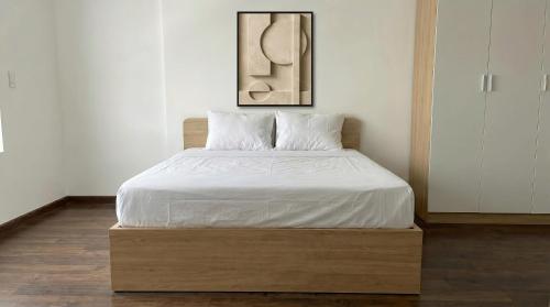 a bed with white sheets and pillows in a room at BenHill - serviced apartment-Binh Duong in Ấp Dừa