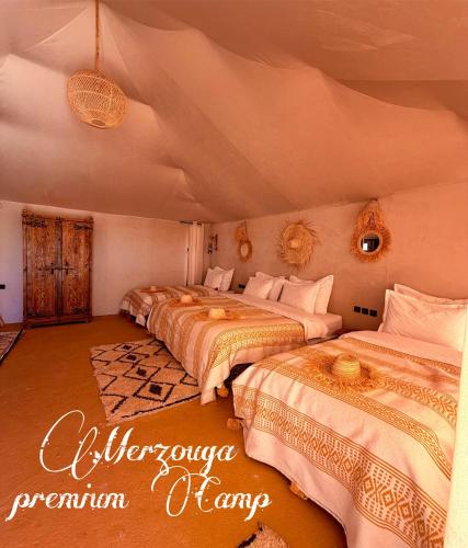 a bedroom with three beds in a room at Merzouga premium Camp in Merzouga