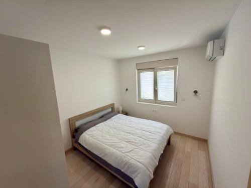 a small bedroom with a bed and a window at Lira Bay in Igalo