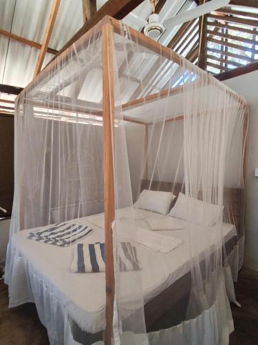 a canopy bed with mosquito netting in a room at Upali Beach Surf Resort in Nikawatawana