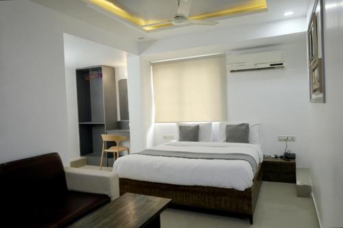 a bedroom with a bed and a table and a couch at HOTEL GOLD LEAF in Ahmedabad