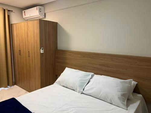 a bedroom with a bed with white sheets and a wooden headboard at Studio-type apartment in Praia do Forte in Mata de Sao Joao