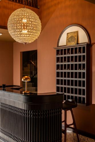 a bar with a stool and a chandelier at Merchant's Gate Songwat in Bangkok