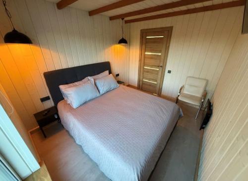 a bedroom with a white bed and a chair at Rūdupji Anna in Kalniena