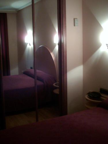 a bedroom with a mirror and two beds and lights at Hotel VillaPaloma in La Virgen del Camino