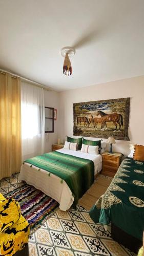 a bedroom with two beds and a painting on the wall at mehek in Asilah