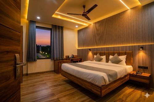 a bedroom with a bed with a ceiling fan and a window at Hotel De Grand Dwarka-Near Jaipur Airport in Jaipur