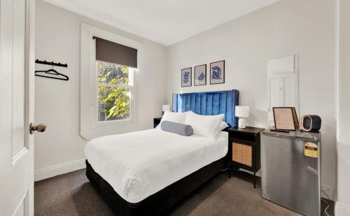 a white bedroom with a bed and a window at Windsor Green Hotel in Melbourne