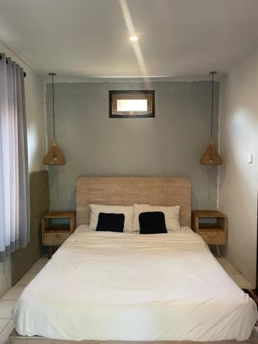 a bedroom with a large white bed with two pillows at Pondok Gopi Room in Cemagi
