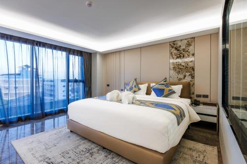 a bedroom with a large bed and a large window at HK Hotel Bangkok in Ban Bang Toei (1)