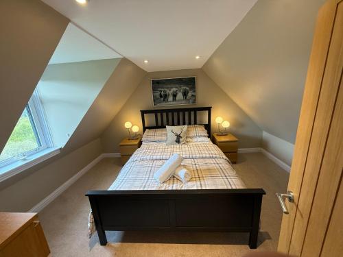 a attic bedroom with a bed with two lamps at Alt-Na-Slat Cottage in Invergarry