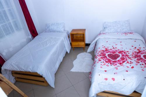 a bedroom with two beds and a night stand at La casa Cottage in Iringa