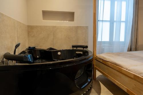 a bathroom with a black bathtub next to a bed at Love Room avec Jacuzzi - Le cocon caché in Bressuire