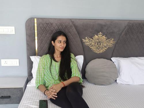 a woman is sitting on a bed at Amazing Valley View in Kasauli