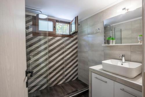 a bathroom with a sink and a mirror at NeonChic Jacuzzi and Pool Villa in Sani Beach