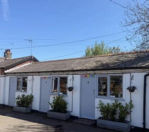 a white house with plants in front of it at The Burrow at Black Rabbit Pub in Haybridge