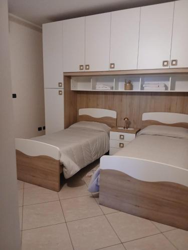 two beds in a room with white cabinets at Spazioso appartamento su due piani in Leinì