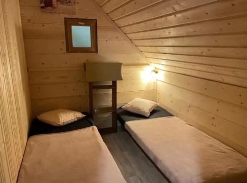 a room with two beds in a log cabin at Camping nature 3 étoiles avec piscine - bord de rivière in Chézery-Forens