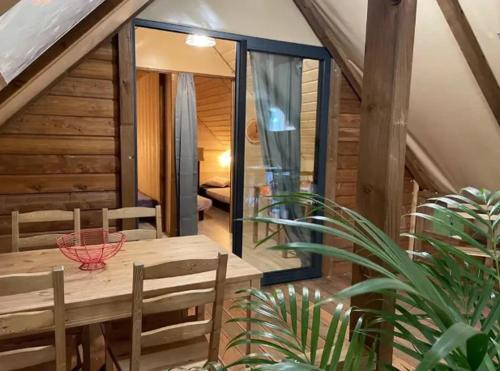 a dining room with a wooden table and chairs at Camping nature 3 étoiles avec piscine - bord de rivière in Chézery-Forens