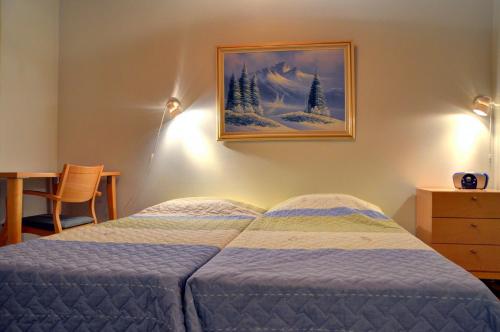 a bedroom with a bed and a picture on the wall at Alppitalo 2 as 1 in Tahkovuori