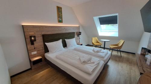 a bedroom with a bed and two chairs and a window at SEKRA Stadthotel in Heidenheim an der Brenz