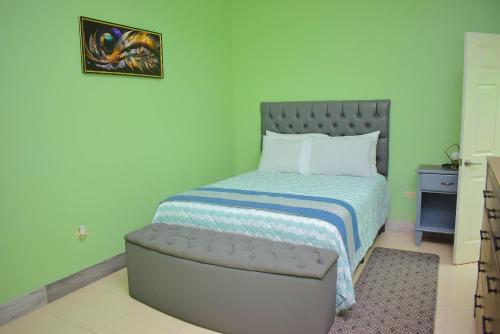a small bedroom with a bed with a blue wall at Cedar Grove Luxe in Portmore