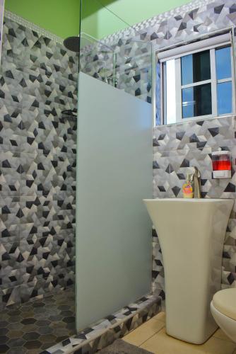 a bathroom with a shower with a toilet and a window at Cedar Grove Luxe in Portmore