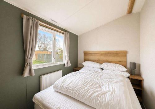 a bedroom with a white bed with a window at Kestrel Court 16 in Scratby