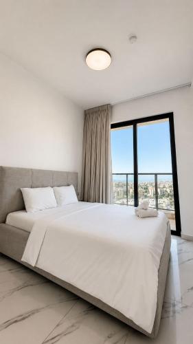 a bedroom with a large white bed with a large window at Penthouse-AH- 77 in Eilat