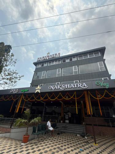 a man sitting in front of a building at Nakshatra Boarding and Lodging in Mangalore International